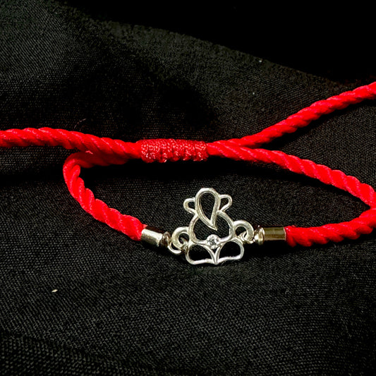 Red cord bracelet with a silver heart-shaped clasp on a black background